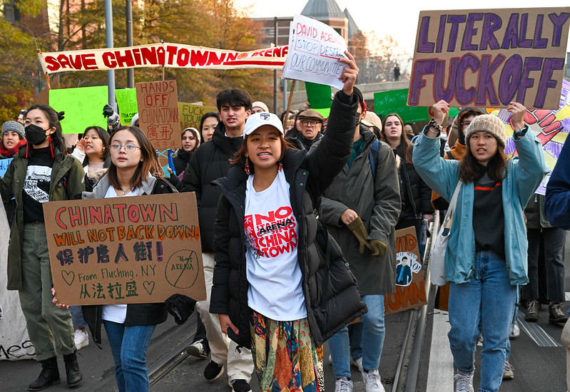 a large group of people hold picket signs that read 'save Chinatown' during a protest in Philadelphia