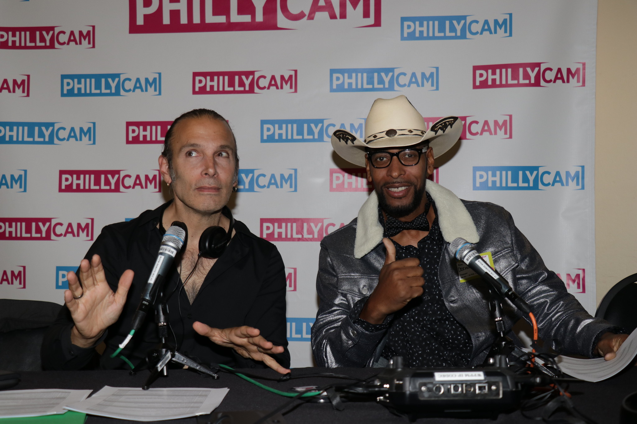 two men sitting in front of microphones places on a table