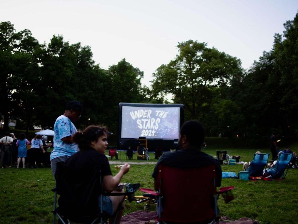 people seated in a park for an outdoor movie screening