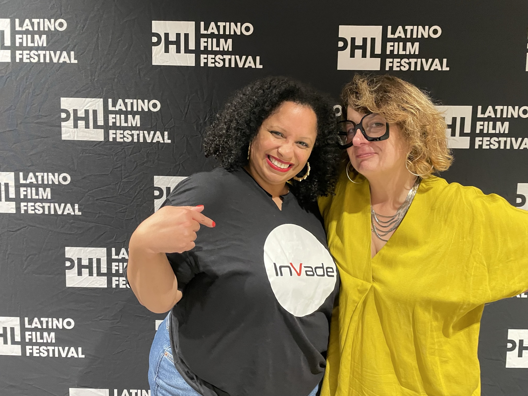 two people stand in front of a red carpet logo backdrop that reads: PHL Latino Film Festival