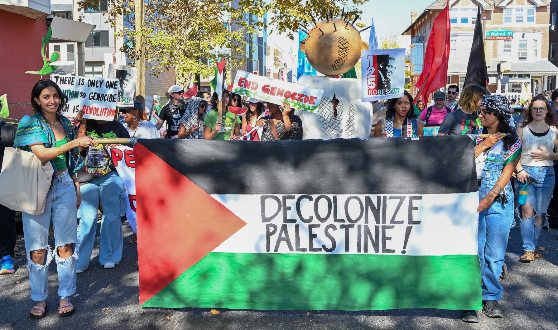 a group of people at a pro-Palestine parade holding a sign that reads "decolonize Palestine"