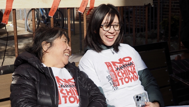 two women seated on a bench laugh together