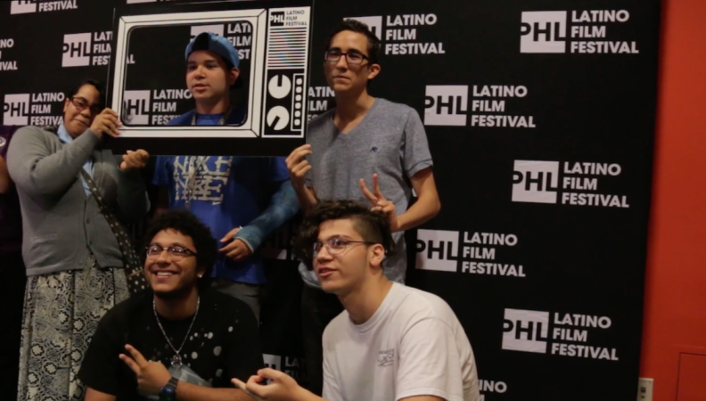 a group of people taking a photo in front of a backdrop that reads PHL Latino Film Festival