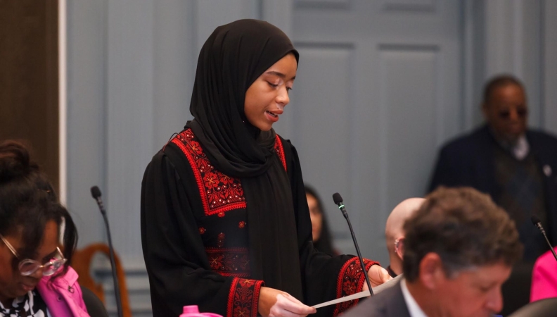 a woman wearing a hijab speaks in a congress of local Delaware politicians