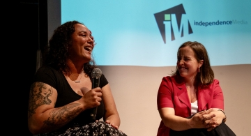 a person holds a microphone while laughing during a panel conversation