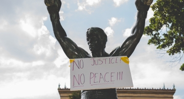 image of Rocky statue with a sign on it saying no justice, no peace