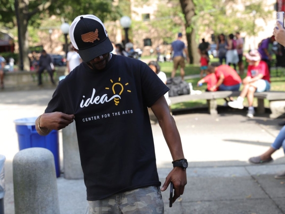 A person looking down and holding their IDEA Center for the Arts t-shirt