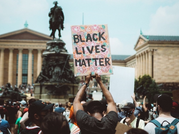a man holds a Black Lives Matter sign at a protest in front of the Philadelphia Art Museum