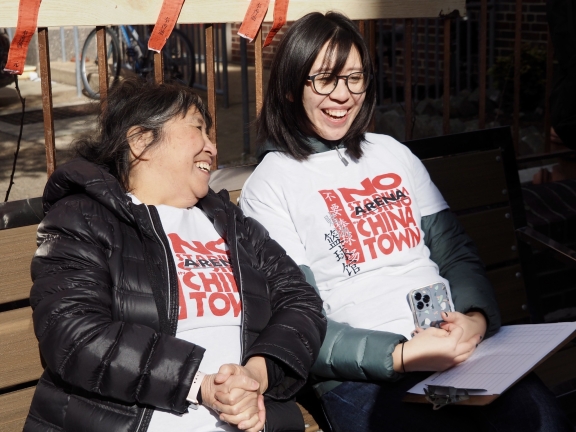 two women seated on a bench laugh together