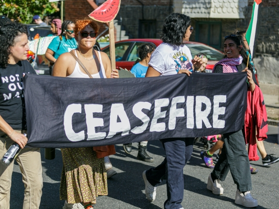 a group of people at a protest hold a sign reading ceasefire
