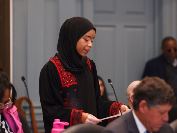 a woman wearing a hijab speaks in a congress of local Delaware politicians