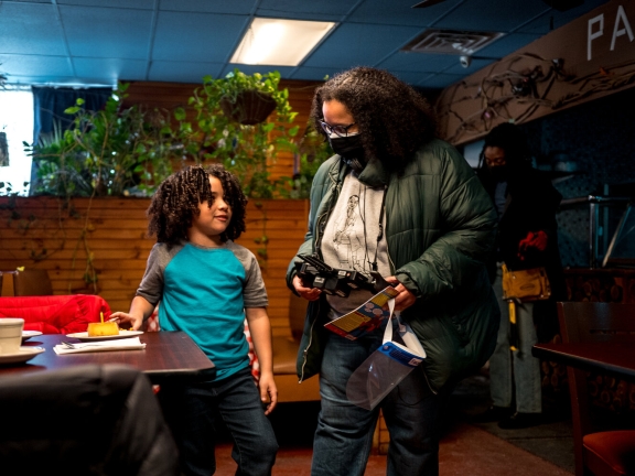 filmmaker holding film equipment in one hand and talking with a child actor standing to their left