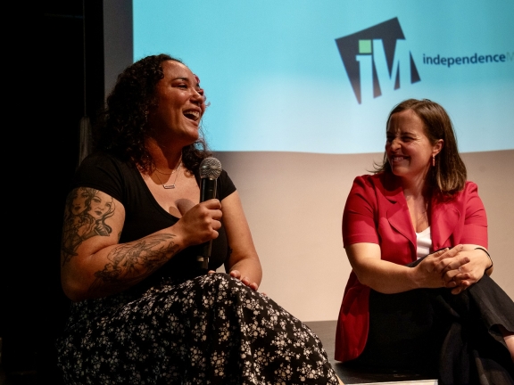 a person holds a microphone while laughing during a panel conversation