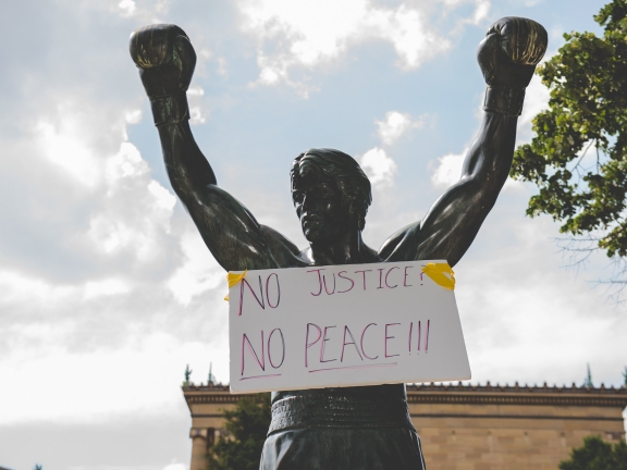 image of Rocky statue with a sign on it saying no justice, no peace