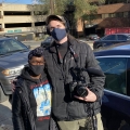 Two people hugging in a parking lot, one holding a camera