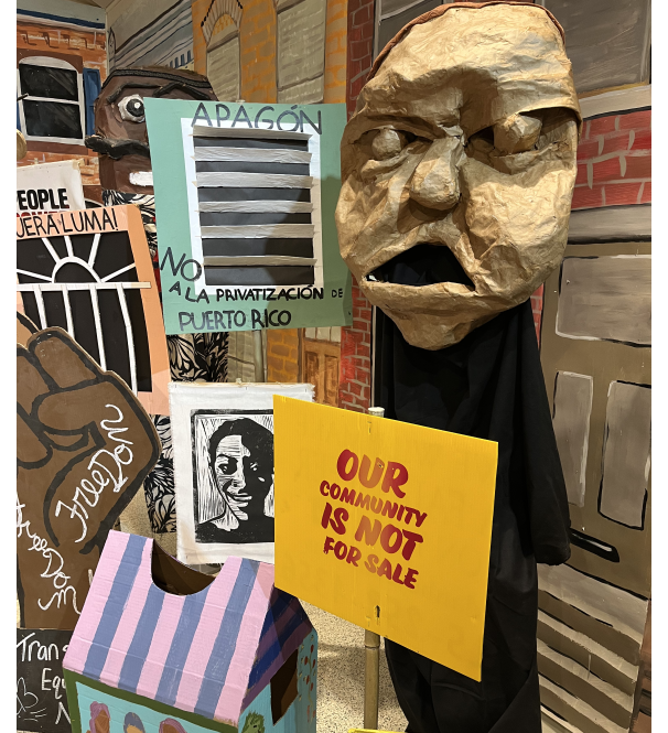 A Spiral Q puppet show display that reads 'our community is not for sale'