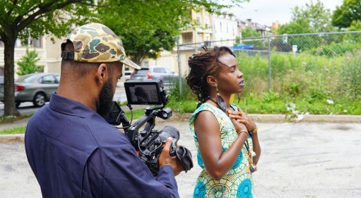 a man filming a woman with her eyes closed and her hands on her chest