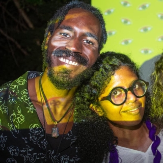 Three people posing for a picture with a yellow background projected onto them